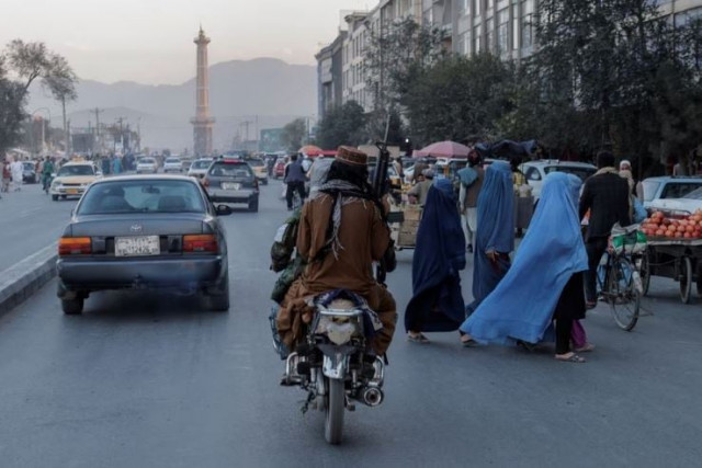 a group of women wearing burqas crosses the street as members of the taliban drive past in kabul afghanistan october 9 2021 photo reuters a group of women wearing burqas crosses the street as members of the taliban drive past in kabul afghanistan october 9 2021 photo reuters