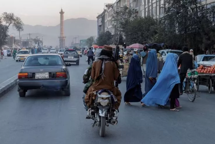 a group of women wearing burqas crosses the street as members of the taliban drive past in kabul afghanistan october 9 2021 photo reuters a group of women wearing burqas crosses the street as members of the taliban drive past in kabul afghanistan october 9 2021 photo reuters