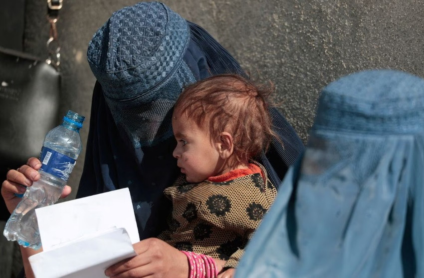 a displaced afghan woman holds her child as she waits with other women to receive aid supply outside an unchr distribution center on the outskirts of kabul afghanistan october 28 2021 reuters zohra bensemra