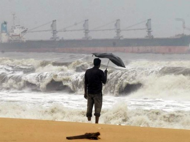 a man holding an umbrella watches large waves on chennai s marina beach in tamil nadu state photo reuters file