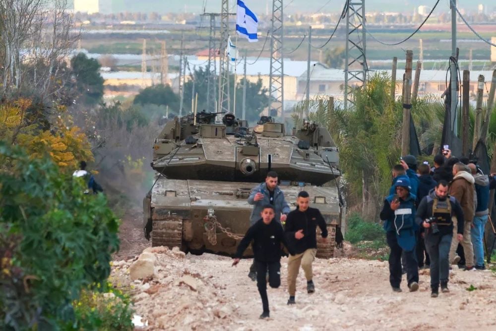 Palestinian children and journalists disperse as Israeli tanks enter the Jenin camp for Palestinian refugees in the occupied West Bank. PHOTO: AFP