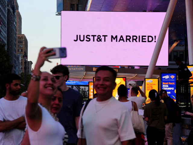 People take selfies next to a screen displaying a message referencing singer Taylor Swift and National Football League (NFL) player Travis Kelce outside Madison Square Garden, the venue for their wedding celebrations, in New York, U.S., July 3, 2026. REUTERS/Angelina Katsanis