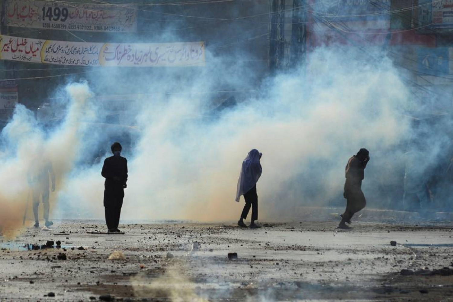 Supporters of the Tehreek-e-Labaik Pakistan run to cover amid the smoke of tear gas fired by police during a protest against the arrest of their leader in Lahore, Pakistan April 13, 2021. Photo: Reuters