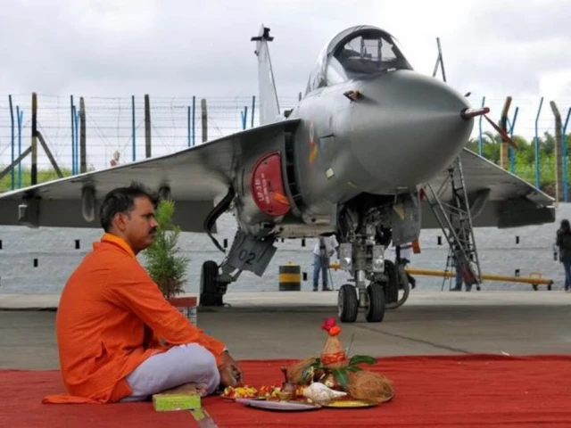a hindu priest waits to perform prayers next to tejas india s first locally built light combat aircraft lca before its induction into the indian air force at the hindustan aeronautics limited hal airport in bengaluru july 1 2016 photo reuters