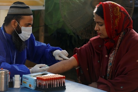 a paramedic wearing protective gloves prepares to take a blood sample from a woman to be tested for the coronavirus disease covid 19 anti body test at a camp in karachi photo reuters