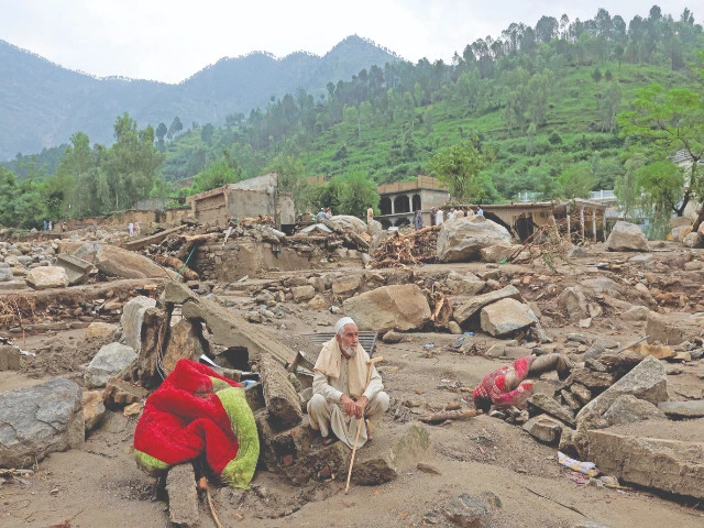 an old man sits on the remains of damaged houses following flash floods in bayshonai kalay in buner district photo reuters