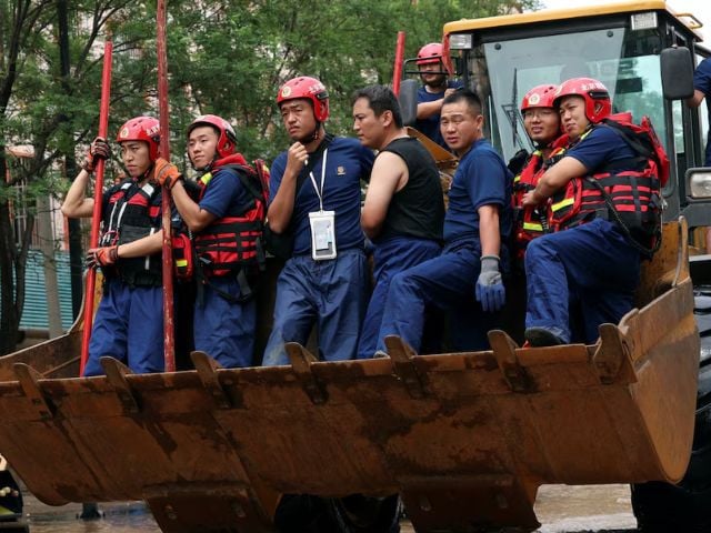 Rescue workers ride on a front loader as they make their way through a flooded road, after heavy rainfall in Miyun district of Beijing, China July 29, 2025. REUTERS/Florence Lo Purchase Licensing Rights
