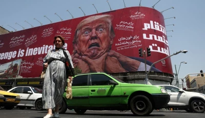 a woman walks near a billboard depicting us president donald trump on a building in tehran iran july 27 2026 wana via reuters
