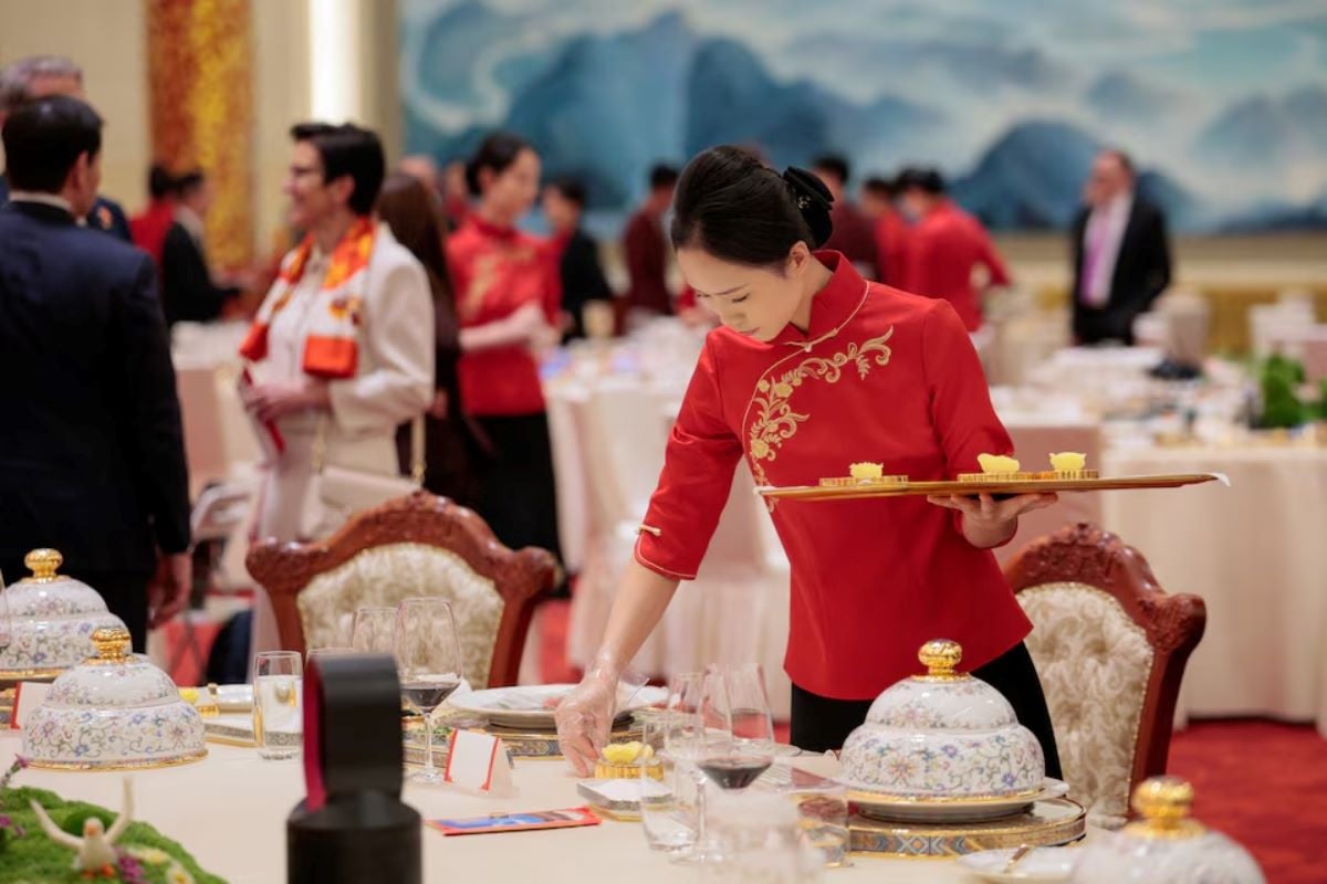 A worker prepares a place setting as attendees arrive for a state banquet with US President Donald Trump and Chinese President Xi Jinping at the Great Hall of the People in Beijing, China, May 14, 2026. REUTERS
