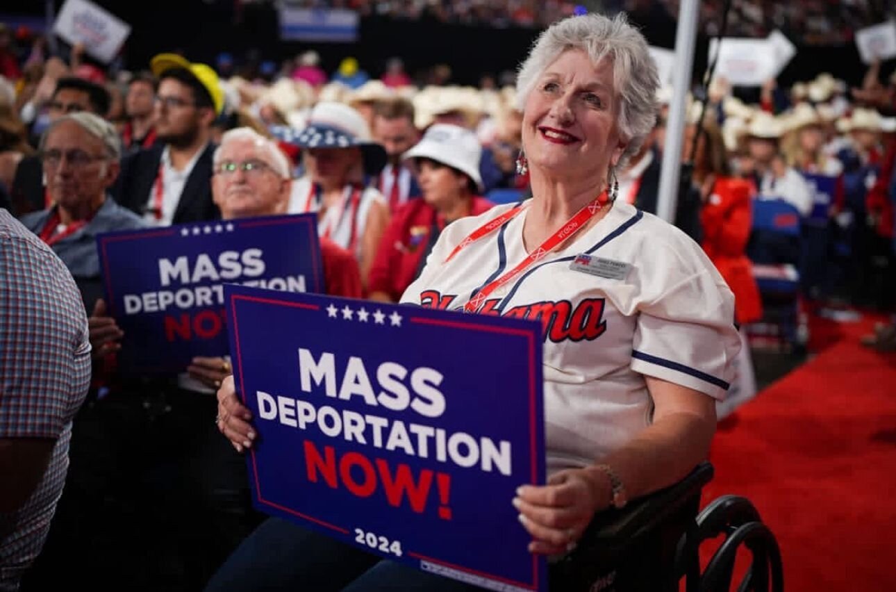 Woman holds 'Mass deportation rally now!' banner at Trump's rally in 2024.