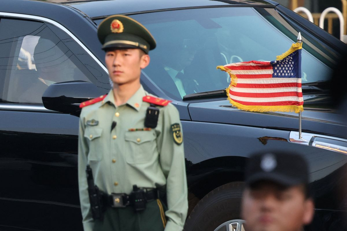 Security officers stand guard as a car with U.S. national flag, in a motorcade carrying US President Donald Trump, passes by during his visit to China, in Beijing, China, May 14, 2026. REUTERS