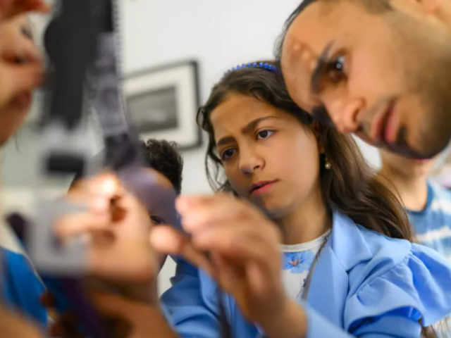 Syrian photographer Serbest Salih (R) works with children during a workshop organized as part of the