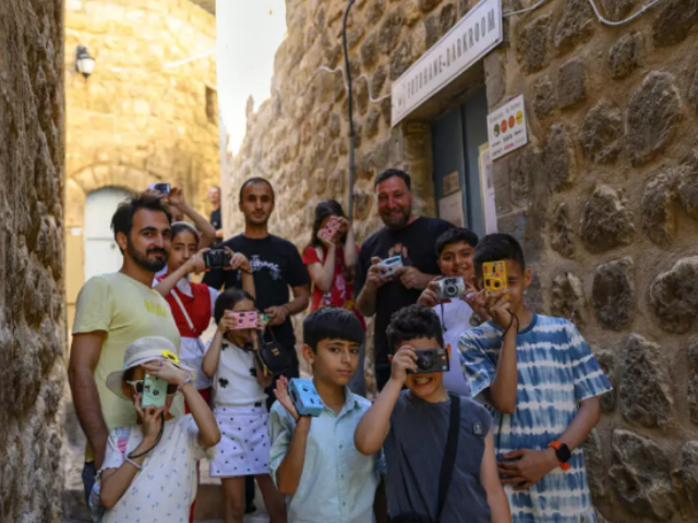 Children develop photographic film with their teachers and photographers Serbest Salih (left) and Amar Kilic (third from right) during a workshop organized as part of the