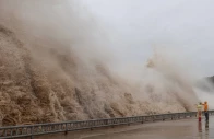 people stand next to huge waves crashing on a waterfront as typhoon dolphin approaches in sanmen county taizhou zhejiang province china august 8 2026 photo reuters