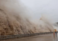 people stand next to huge waves crashing on a waterfront as typhoon dolphin approaches in sanmen county taizhou zhejiang province china august 8 2026 photo reuters