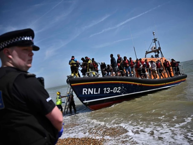a british police officer stands guard on the beach of dungeness on the southeast coast of england as royal national lifeboat institution s rnli members help migrants to disembark from one of their lifeboats after they were picked up at sea while attempting to cross the english channel june 15 2022 photo afp a british police officer stands guard on the beach of dungeness on the southeast coast of england as royal national lifeboat institution s rnli members help migrants to disembark from one of their lifeboats after they were picked up at sea while attempting to cross the english channel june 15 2022 photo afp