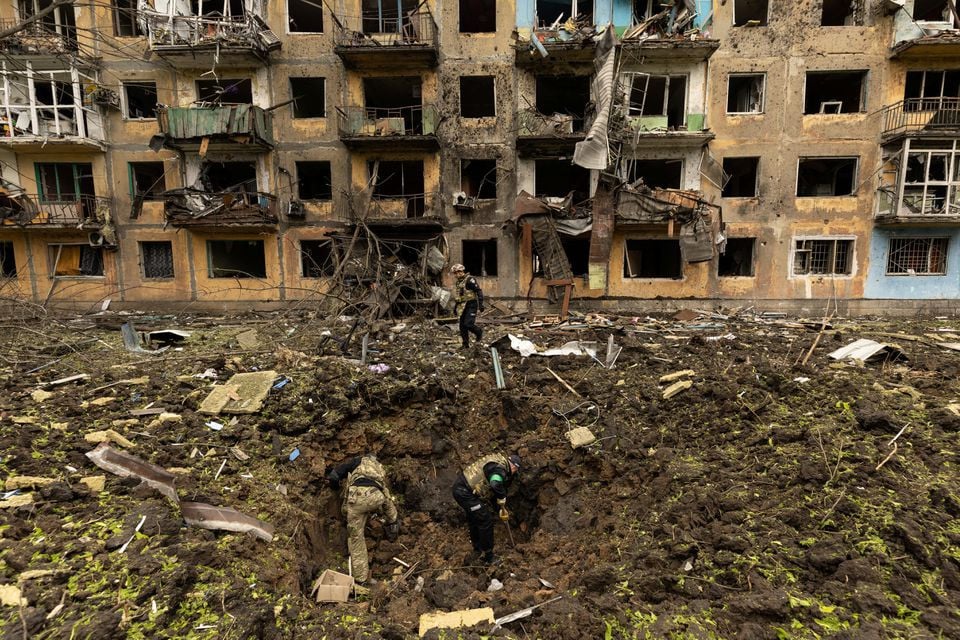 Ukrainian military personnel inspect the site of a missile strike in front of a damaged residential building, amid Russia's invasion, in Dobropillia, in the Donetsk region, Ukraine, April 30, 2022. PHOTO: REUTERS