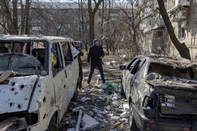 a man walks near destroyed cars in a residential district that was damaged by shelling as russia s invasion of ukraine continues in kyiv ukraine march 18 2022 photo reuters