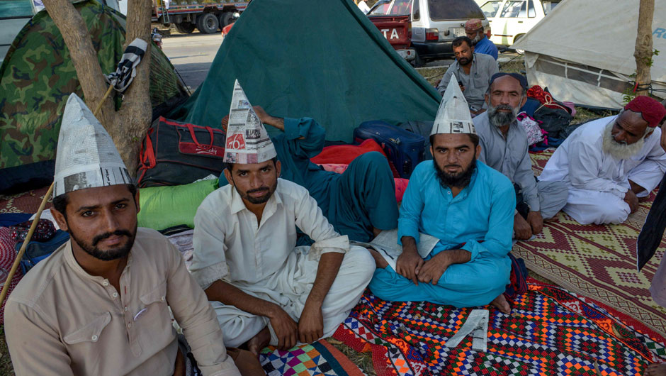 Opposition activists look on as they wear caps made with newspapers during an anti-government 