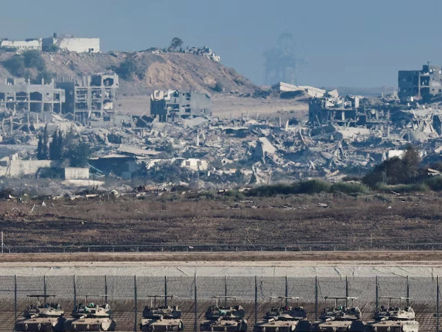 tanks stand on the israeli side of the border as destruction in gaza is seen in the background photo reuters