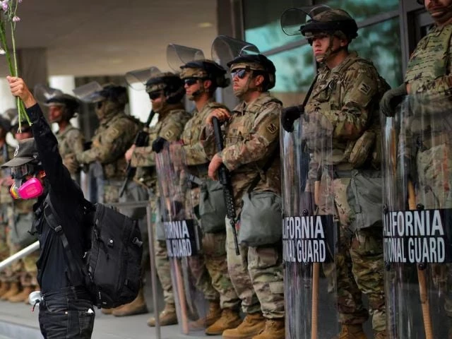 demonstrator raises his hand holding flowers as members of the national guard stand in formation outside a federal building during the no kings protest against u s president donald trump s policies in los angeles california u s june 14 2025 photo reuters demonstrator raises his hand holding flowers as members of the national guard stand in formation outside a federal building during the no kings protest against u s president donald trump s policies in los angeles california u s june 14 2025 photo reuters