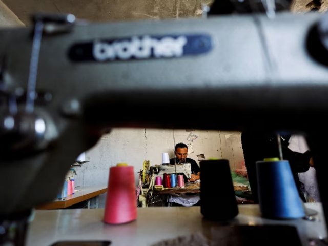 Photo: A Palestinian tailor repairs and recycles wedding dresses and children's gowns at a workshop/Reuters