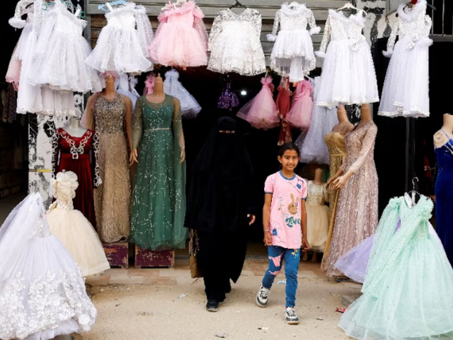 Photo: Palestinian woman and a girl walk out of a wedding dress shop/Reuters