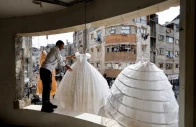 photo palestinian man hangs wedding dresses at a shop with damaged walls and ceiling reuters