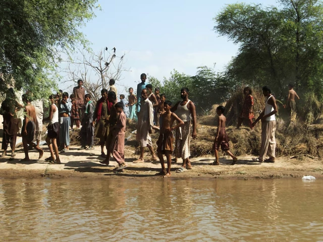 flood victims stand as they wait for food handouts following monsoon rains and rising water levels of the chenab river in seetpur punjab province pakistan september 13 2025 photo reuters