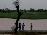 residents stand on a higher ground with the flooded field in the background following monsoon rains and rising water levels of the chenab river in patraki village chiniot district punjab province pakistan august 30 2025 photo reuters