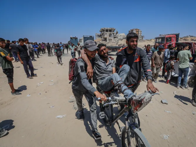 Palestinians carry a wounded man on a bicycle after Israeli forces attack a crowd gathered to receive aid in northern Gaza. Photo: Anadolu