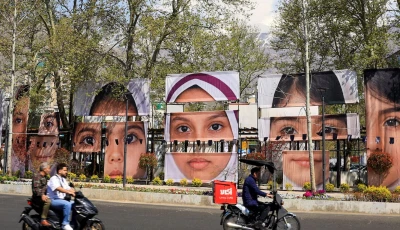 people on motorcycles ride along a street past banners showing portraits of students killed in a us israeli strike on a girls school during the us israeli war on iran amid a ceasefire at tajrish square in tehran iran april 15 2026 reuters