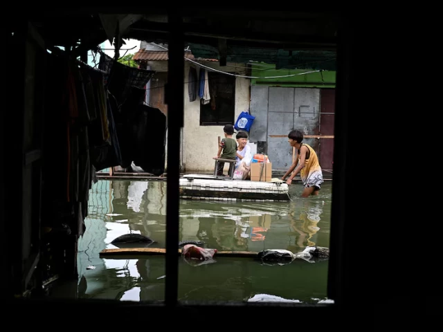 children use a makeshift raft to cross a flooded street following rains intensified by severe tropical storm bualoi in dela paz binan laguna province philippines september 26 2025 photo reuters