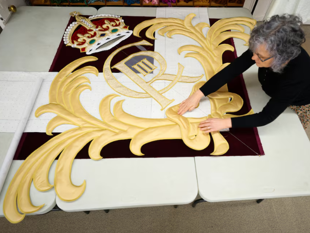 Studio manager Gemma Murray arranges embroidery pieces/ Reuters