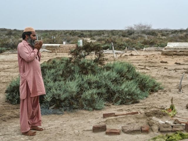 Habibullah Khatti bids a final goodbye to his mother's grave before he abandons his parched island village on Pakistan's Indus delta  Asif HASSAN / AFP