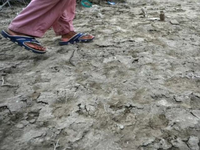 Habibullah Khatti, a local resident, walks over the salt crusts deposited in Kharo Chan town Asif HASSAN / AFP