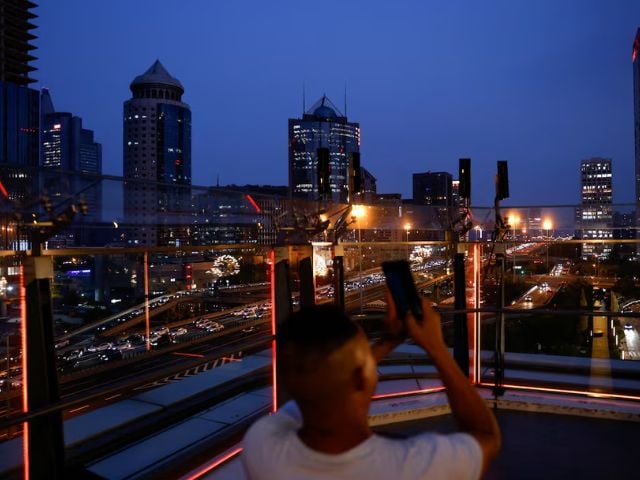 A person takes pictures on a terrace of a shopping mall overlooking the central business district (CBD), in Beijing, China August 11, 2025. Photo: Reuters