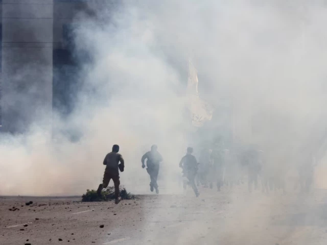 police officers and supporters of tehreek e labbaik pakistan tlp run amid tear gas fired by police during a solidarity march for gaza in lahore pakistan photo reuters