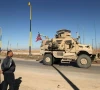 men watch as a us military mine resistant ambush protected mrap armored fighting vehicle moves in a convoy along a highway outside qamishli in syria s northeastern hasakeh province on february 23 2026 photo afp