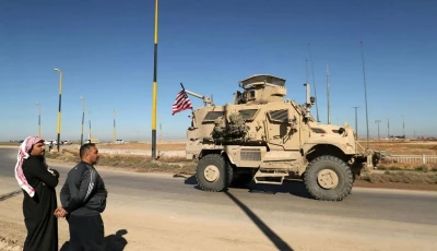 men watch as a us military mine resistant ambush protected mrap armored fighting vehicle moves in a convoy along a highway outside qamishli in syria s northeastern hasakeh province on february 23 2026 photo afp
