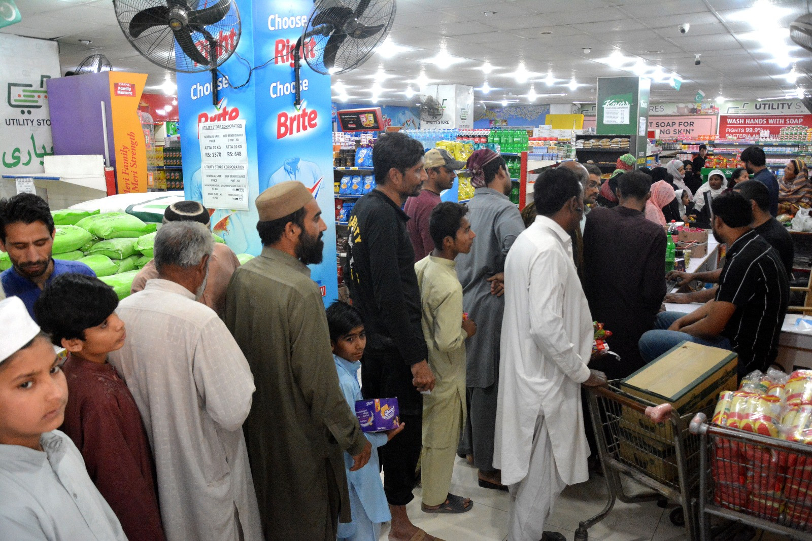 people stand in line to buy essential food items on subsidised rates at an outlet of the state run utility stores corporation in dha karachi on friday photo jalal qureshi express