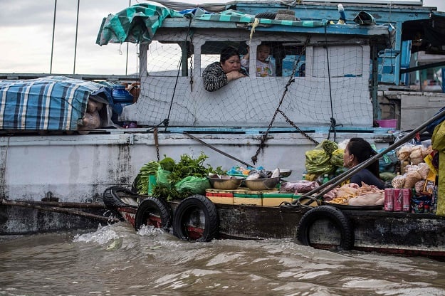 A boat vendor offers her vegetables to a house boat resident in a canal off the Song Hau river in the floating Cai Rang market in Can Tho, a small city of the Mekong Delta. PHOTO: AFP