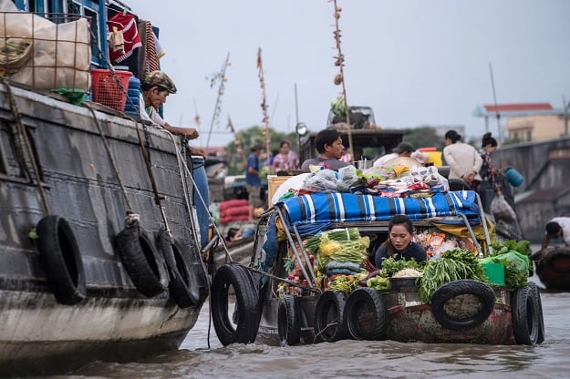 A vendor (R) prepares vegetables that she sold to a resident of a house boat in a canal off the Song Hau river in the floating Cai Rang market in Can Tho, a small city of the Mekong Delta. PHOTO: AFP