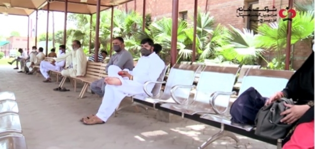 The picture shows patients waiting in an open environment, outside the Walk-in Clinic, keeping minimum safe distance between each other, to reduce crowding inside the Clinic