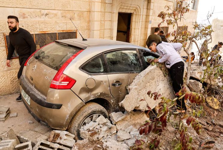 palestinians stand near a damaged vehicle near the site where a number of palestinians were killed in an israeli raid in jenin in the israeli occupied west bank march 11 2025 photo reuters