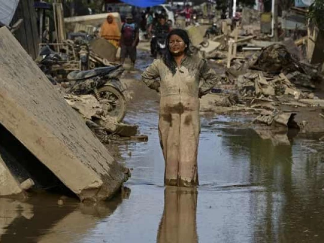 a woman covered in mud stands on a street filled with mud after a flash flood hit the area in aceh tamiang aceh province photo afp