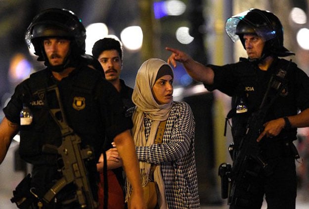 Spanish policemen accompany clients of a store outside a cordoned off area after a van ploughed into the crowd, killing 13 persons and injuring over 80 on the Rambla in Barcelona on August 17, 2017. PHOTO: AFP